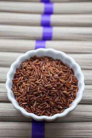 A bowl full of red rice over rice noodles.の写真素材