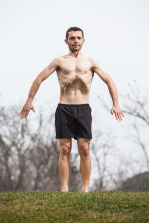 man performing abdominal exercise standing on the grass