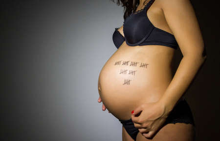 pregnant woman posing with paint on her bellyの写真素材