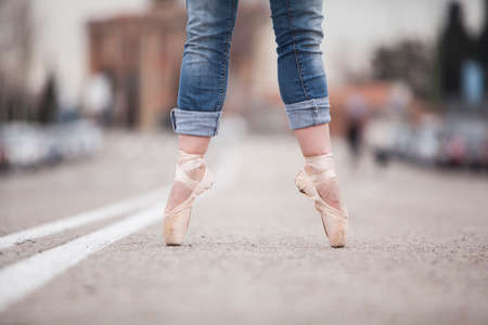 woman dancer on ballet tips and jeans on the street and legs apartの写真素材