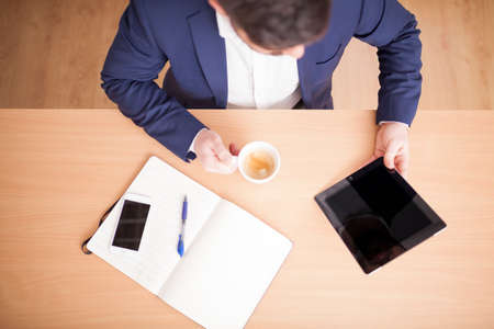 businessman in suit in meeting room with tablet and coffee aerial viewの写真素材