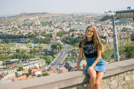The girl is beautiful. On the background of the city. The view from the top. panorama. A stone fence. Old Tbilisiの写真素材