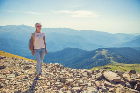 Happy woman traveler in the mountains and the landscape of mountains and blue sky Travel lifestyle concept of adventure summer holidays.の写真素材