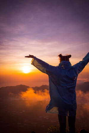The girl in the raincoat on the Batur volcano. Silhouette. Sun. Sunset. Mountains.の写真素材