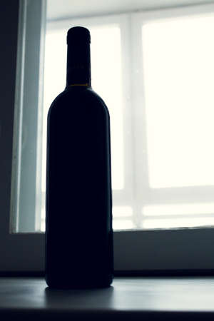 A dark bottle of wine in the Contour light. In the background lightの写真素材