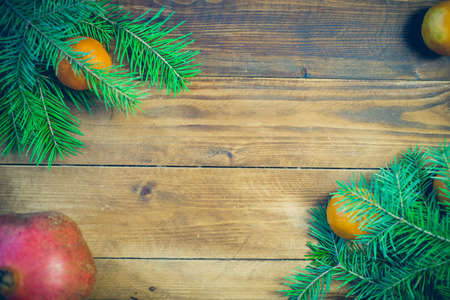 Christmas background with fir tree and decoration on dark wooden board tangerines, fruit, garnet,の写真素材