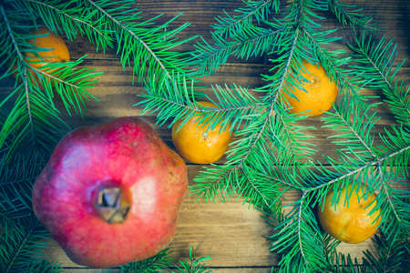 Christmas background with fir tree and decoration on dark wooden board tangerines, fruit, garnet,の写真素材