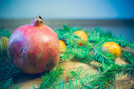 Christmas background with fir tree and decoration on dark wooden board tangerines, fruit, garnet, light backgroundの写真素材