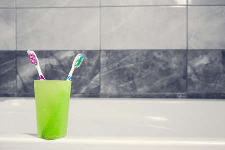 Toothbrushes in a glass on counter. background bath and marble. faucet