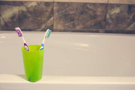 Toothbrushes in a glass on counter. background bath and marble. faucetの写真素材