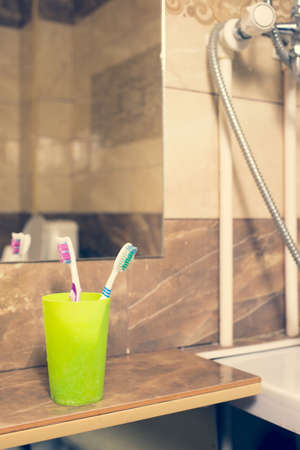 Toothbrushes in a glass on counter. background bath and marble. faucetの写真素材