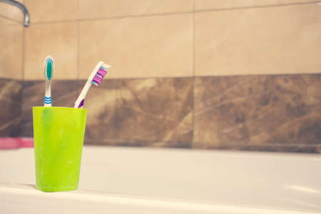 Toothbrushes in a glass on counter. background bath and marble. faucetの写真素材