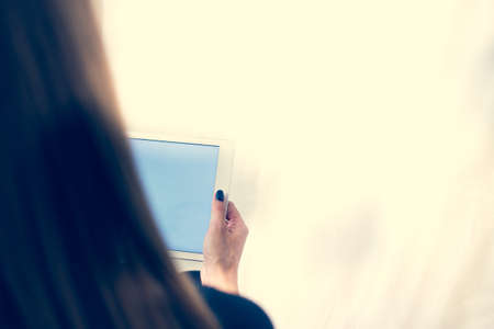 Girl on a tablet computer, browses the information. The white background and the screen.の写真素材
