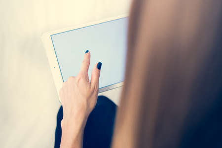 Girl on a tablet computer, browses the information. The white background and the screen.の写真素材