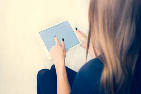 Girl on a tablet computer, browses the information. The white background and the screen.の写真素材