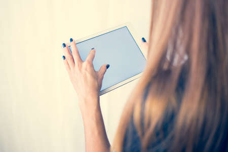 Girl on a tablet computer, browses the information. The white background and the screen.の写真素材