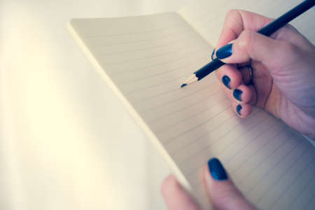 Beautiful woman in a black dress with an open notebook with pen and pencil, Studio isolated on white backgroundの写真素材