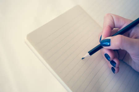 Beautiful woman in a black dress with an open notebook with pen and pencil, Studio isolated on white...