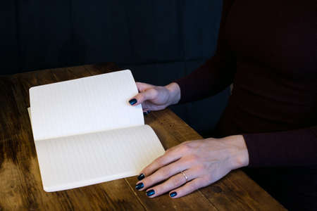 Beautiful woman in a black dress with an open notebook, Studio isolated on black background