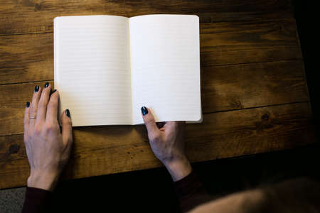 Beautiful woman in a black dress with an open notebook, Studio isolated on black backgroundの写真素材