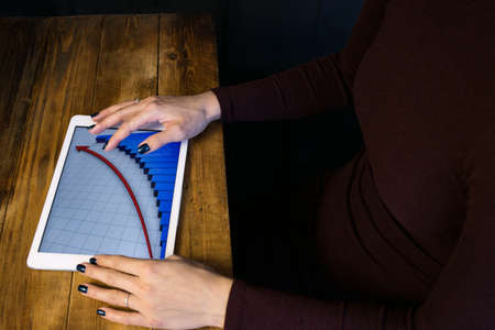 The girl working with a tablet computer. The graph rises. Table, wooden, background blackの写真素材
