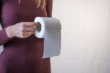 woman take toilet paper. Burgundy dress and white background.の写真素材