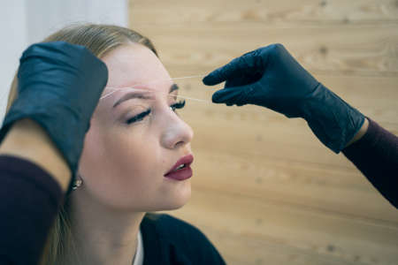 Close-up of female face during eyebrow correction procedure.の写真素材