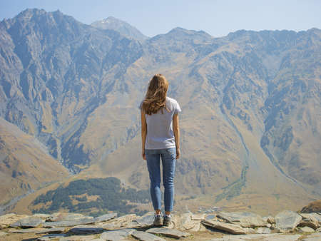 Hiker with backpack standing on top of the mountain and enjoying valley view at sunrise.の写真素材