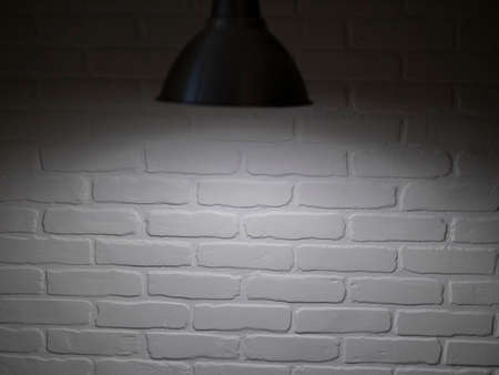 Stone blank wall illuminated with hanging above lamp. Place for text