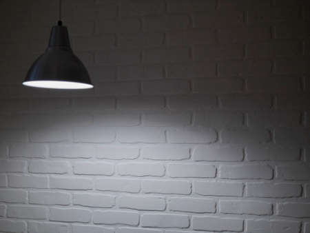 Stone blank wall illuminated with hanging above lamp. Place for textの写真素材