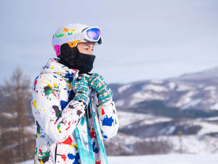 girl holding skis in her hands Happy girl holding skis and ski poles in hands, sitting in snowの写真素材