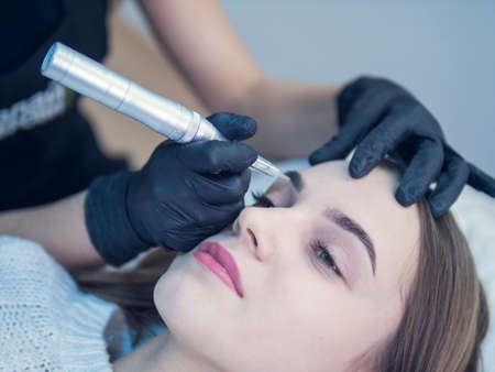 Permanent make up on eyebrows. Master at work with the eyebrows makes microbleeding tattooの写真素材