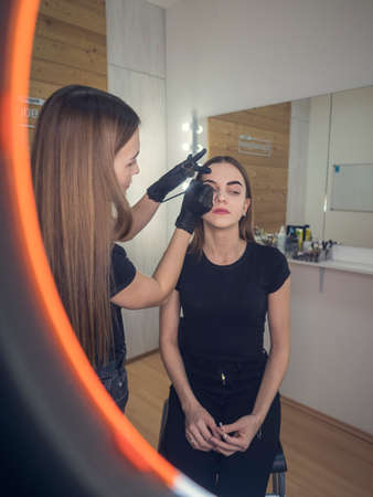 Master at work with the eyebrows making the young girl frown. Draw eyebrows with a pencil. In the...