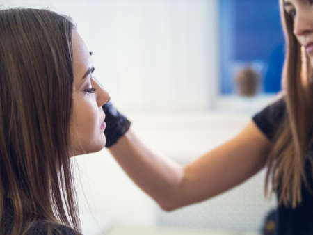Make-up artist combing eyebrow on model's face.