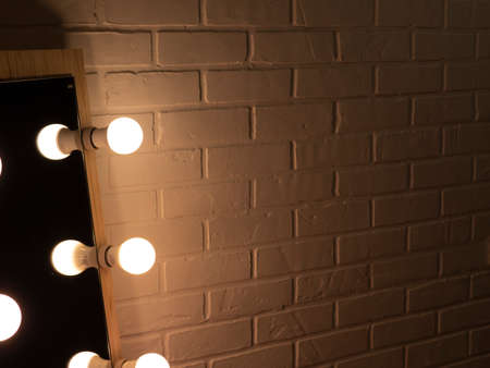 brick wall and three ceiling lamp. warm light yellow. make-up mirror with light bulbs