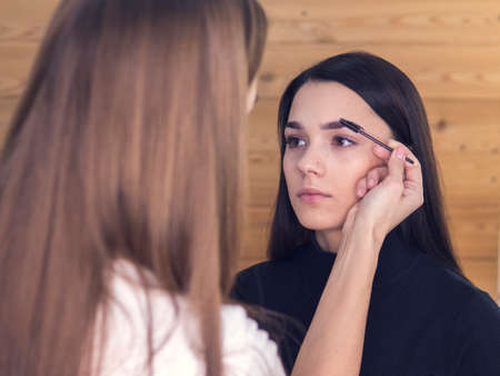 Do make out correct eyebrows. attractive brunette woman black dress looking in round mirror light,...