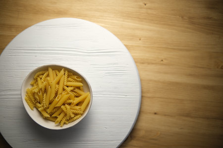 Round white plate with pasta on the left of the frame. On the background of a wooden table. The view from the top.の写真素材