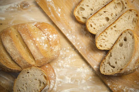 Bread sliced and freshly baked on a wooden table. Flour, bakery. The cooking process is captured in...