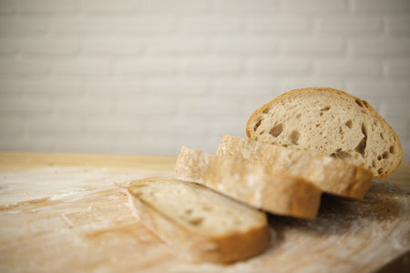 Bread sliced and freshly baked on a wooden table. Flour, bakery. The cooking process is captured in...