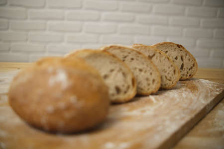 Bread sliced and freshly baked on a wooden table. Flour, bakery. The cooking process is captured in...