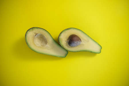 Food background with fresh organic avocado on yellow background. top view, two halves.の写真素材