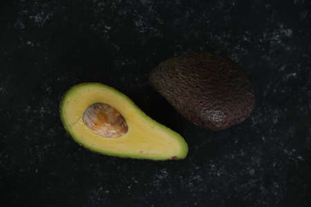 avocado on a black texture background. selective focus. Half of it. Healthy food