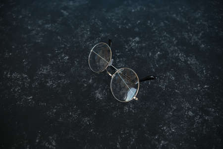 Silver metal glasses. On a solid black stone background. With a soft blurred electoral background. Eyepieces, Vision. top view.の写真素材