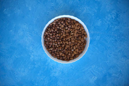 A wooden bowl with mixed nuts on top of a blue table. Healthy food and snacks. Nuts, pistachios,...