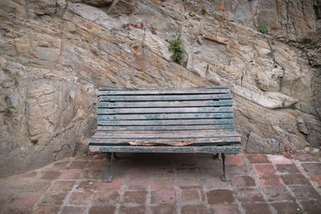 an old bench on the background of a rock wall in the mountains.の写真素材