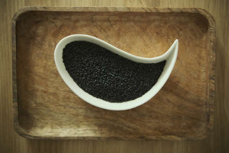 White sesame and black sesame seeds on a white plate. Wooden table. Soft selective blurred background. Top viewの写真素材