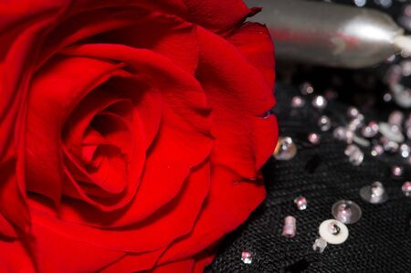 Red rose, black background, candle and sequinsの写真素材