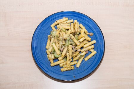 Pasta with pistachio, bacon and zucchini in a blue plateの写真素材
