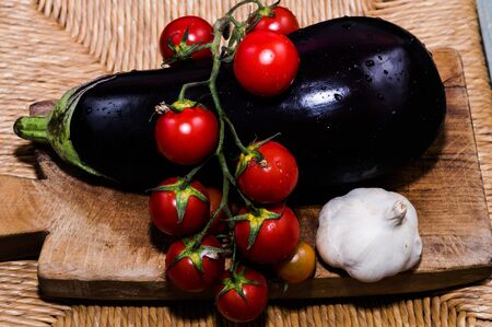 Cutting board with tomatoes, eggplant and garlicの写真素材