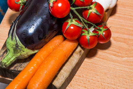 Cutting board with tomatoes, eggplant and carrotsの写真素材